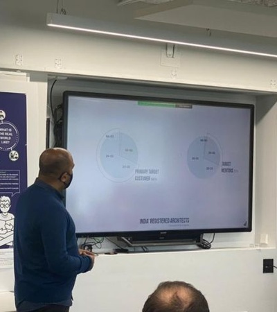 A speaker presenting information on a screen in a modern meeting space.