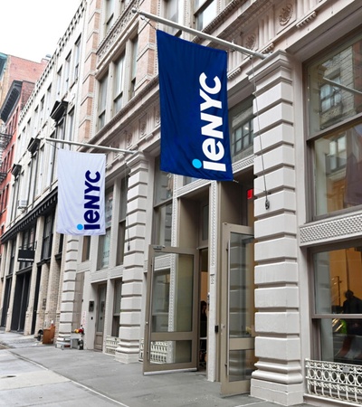 A street scene featuring buildings with flags displaying the logo 'ieNYC'.