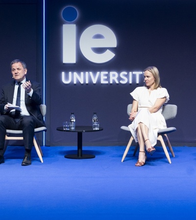 Four professionals are seated on stage at a panel discussion at IE University.