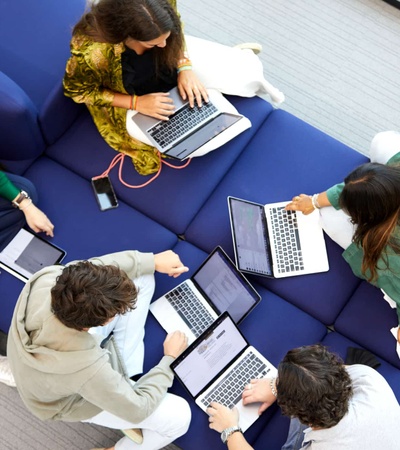 A group of students collaborating on laptops in a casual setting.