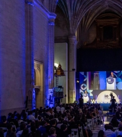 An event is taking place in a large cathedral, with an audience focused on a speaker at the front, illuminated by blue lights.