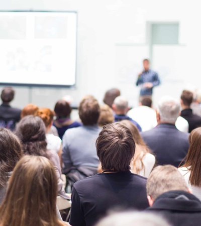 A crowd of people attending a presentation in a lecture hall.