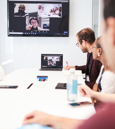 A team meeting conducted via video conference with participants in a modern office setting.
