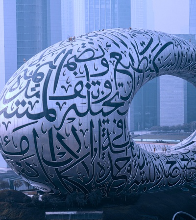 A large, futuristic sculpture featuring intricate calligraphy in an urban setting.