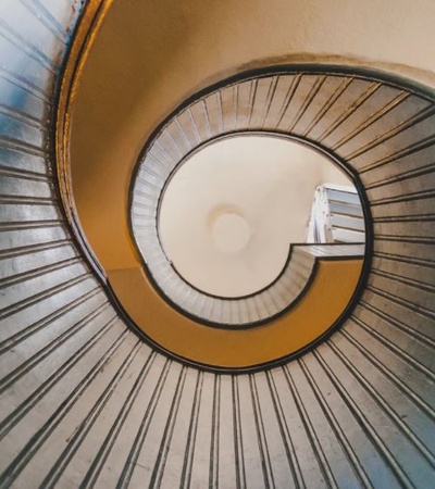 View from the top of a spiral staircase with a distinct spiral pattern and contrasting colors.