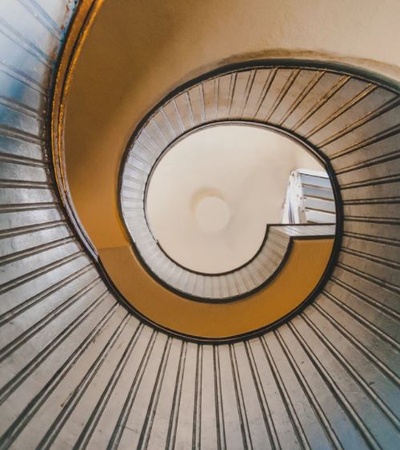 View from the top of a spiral staircase with a distinct spiral pattern and contrasting colors.