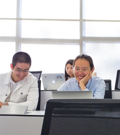A group of students enjoying their time in a classroom with laptops.
