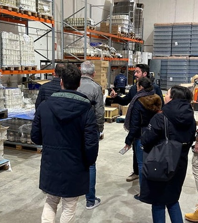 A group of people is observing products in a warehouse environment.