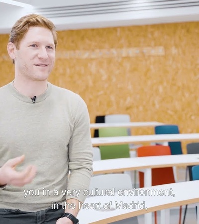 A man speaks in a modern classroom setting.