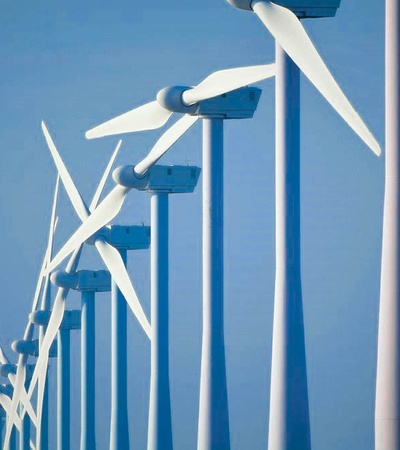 A line of wind turbines against a clear blue sky.