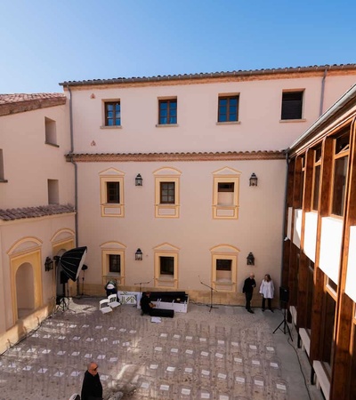A spacious outdoor event setup with rows of chairs arranged in front of a building under a clear blue sky.