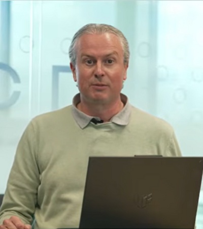 A person standing in front of a laptop while presenting in an office environment.