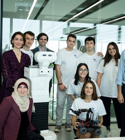 A group of individuals posing with a robot in a modern office setting.