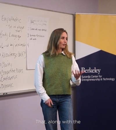 A woman presenting in front of a whiteboard in a classroom with a 'Berkeley Startup Center' banner.