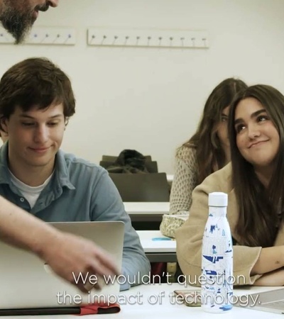 A classroom scene where students are engaged in a discussion about technology's impact.