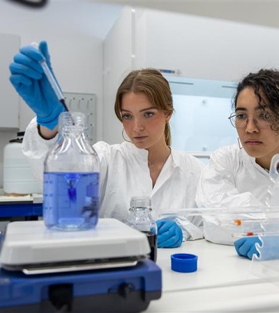 Two women in lab coats are conducting an experiment in a laboratory.