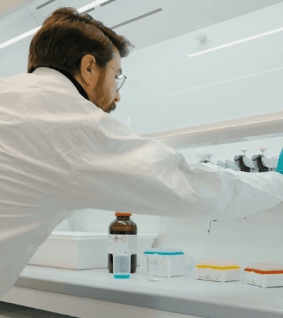 A scientist is working in a laboratory environment, handling various containers and equipment.