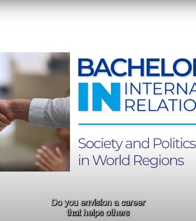 Two people shaking hands next to a poster for a Bachelor in International Relations program.