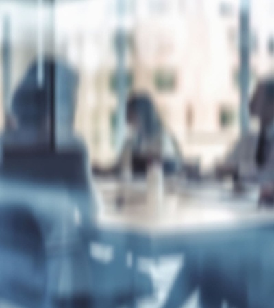 A blurred view of people engaged in a meeting around a table.