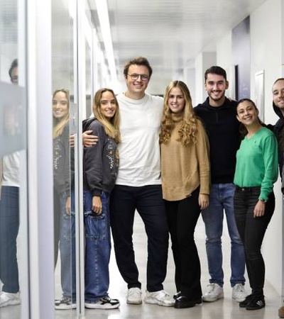 A group of young adults smiling in a bright corridor.