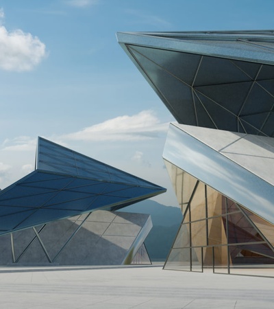 A modern architectural complex with angular buildings made of glass and metal under a clear sky.