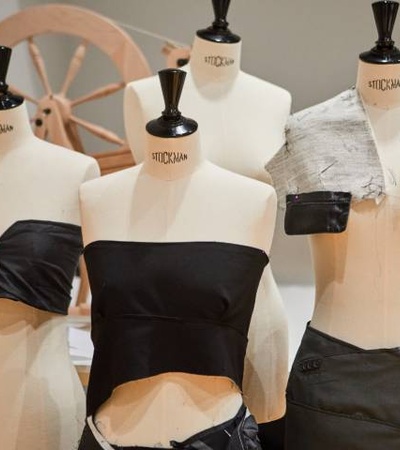 Several fashion mannequins displaying various garments in a workshop setting.