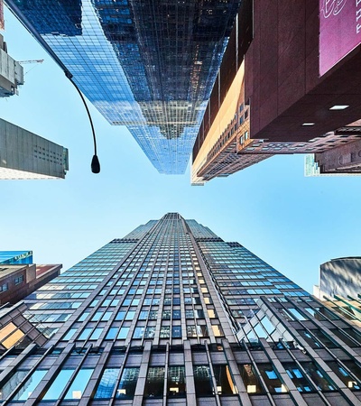 A view looking up at tall buildings with a clear blue sky above.