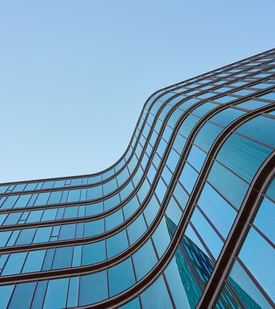 A modern building with flowing glass architecture against a clear sky.
