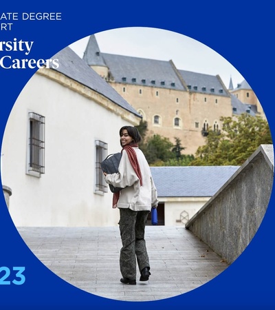 A young woman walks on a campus with historical buildings in the background, featured on a promotional cover for IE University's Career Report for the Class of 2023.