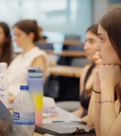 Young women sitting and focusing intently in a classroom setting with laptops open.