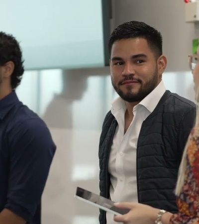 Three young professionals engaging in a discussion in a modern office environment.