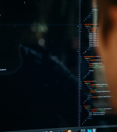 A person focused on coding on a computer screen displaying lines of code.