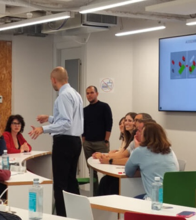 A man is presenting a business strategy to a group of attentive listeners in a seminar room.