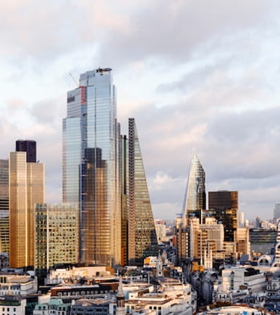 A panoramic view of a modern city skyline with skyscrapers under a cloudy sky.