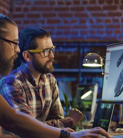 Two men working on a computer design of a drone in a modern office environment.