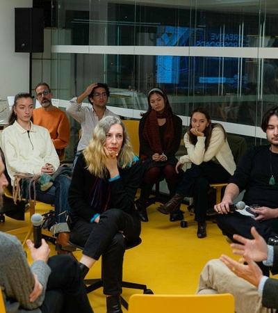 A group of people are engaged in a discussion inside a modern office environment.