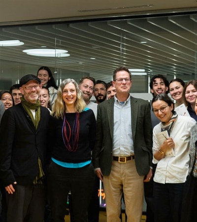 A group of approximately twenty people posing for a photo in a modern office setting.