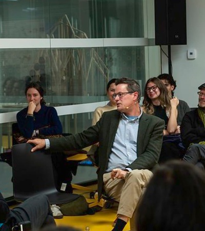 A group of people sitting in a semi-circle in a modern office environment, engaging in a discussion.