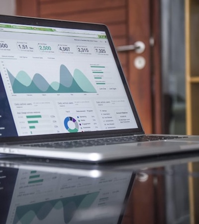 A laptop displaying financial graphs and data analytics on its screen.