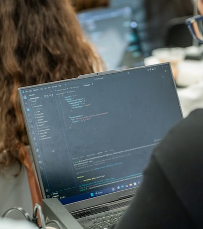 A person coding on a laptop in a classroom setting.