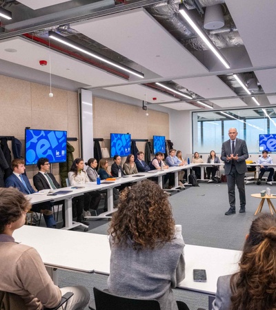 A presentation is taking place in a modern conference room with a group of people seated and attentively listening.