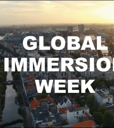 Aerial view of a city at sunset with the text 'GLOBAL IMMERSION WEEK' overlaid.