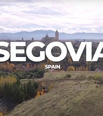 Aerial view of Segovia, Spain, showcasing its historic architecture surrounded by autumn-colored trees.