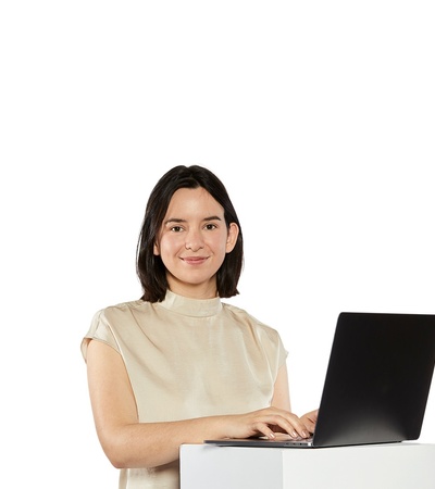 A woman smiling while working on a laptop.