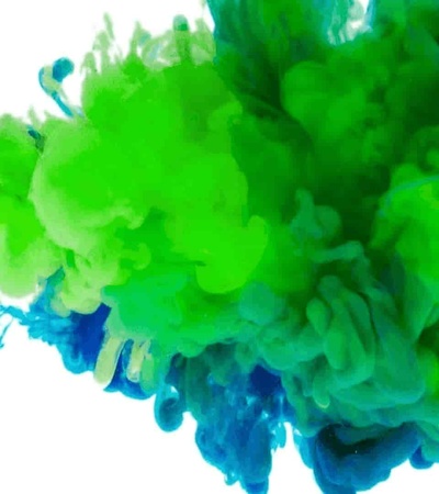 Colorful ink clouds swirling in water, displaying a vibrant transition from blue to green.