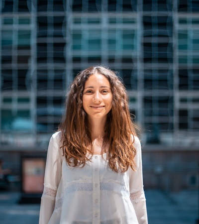 A young woman smiling in front of a modern building