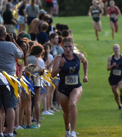 A female runner competing in a race with spectators cheering in the background.