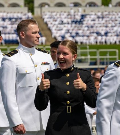 A group of military personnel celebrating with one person enthusiastically giving a thumbs up.