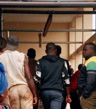 People are seen standing at the back of an open transport vehicle, possibly loading or unloading goods.