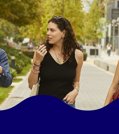 Three young adults walking and talking together in a park-like setting.